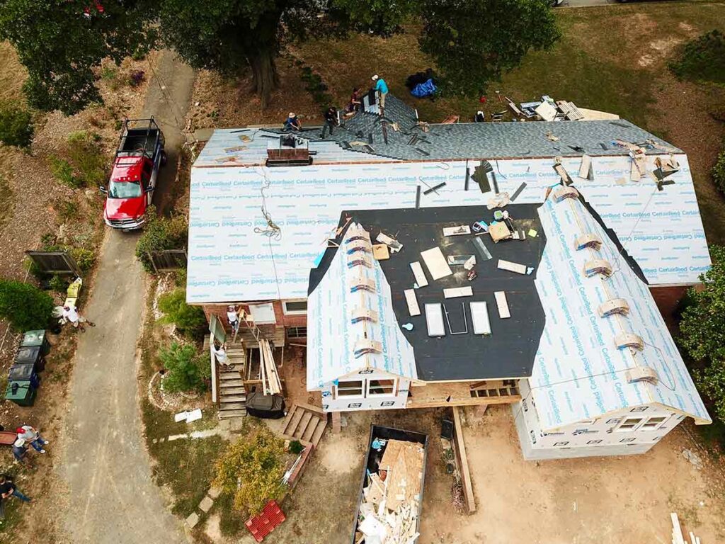 Roofing contractor installing shingles on a house.