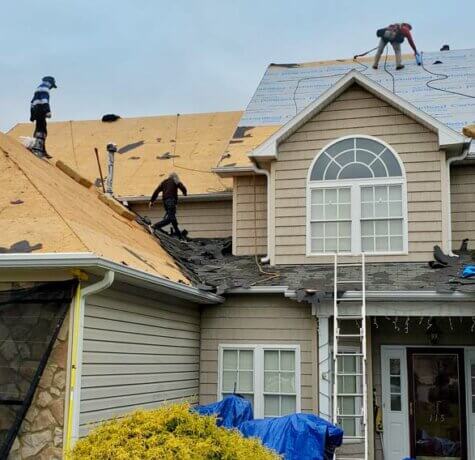 Team of professional roofers, working with top roofing companies in Winston-Salem, install a two-story home's roof.